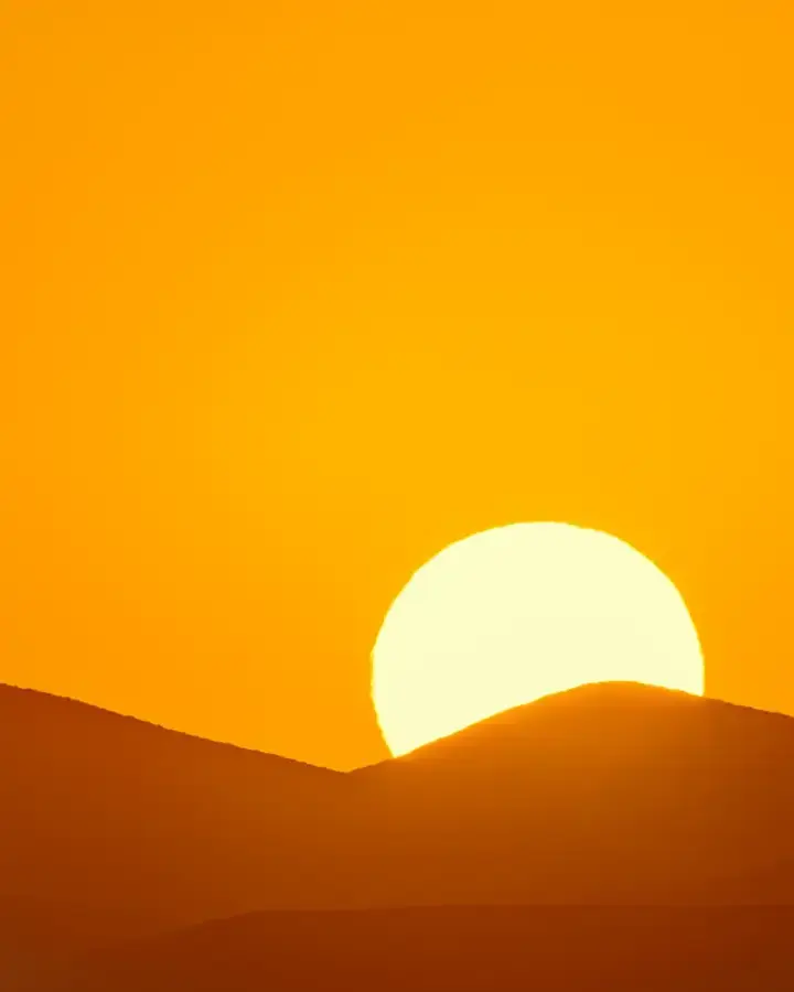 the sun is setting over the mountains