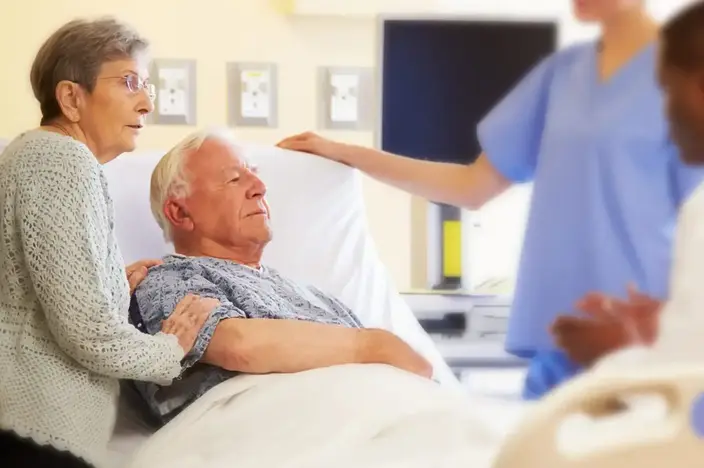 group with elderly patient in bed