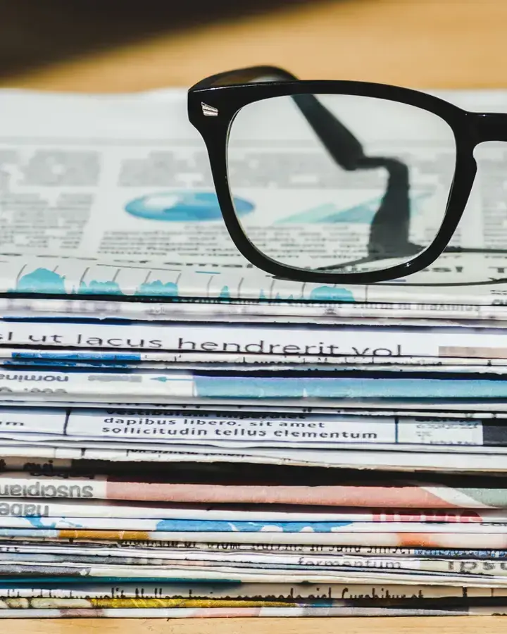 a stack of newspapers with glasses on top