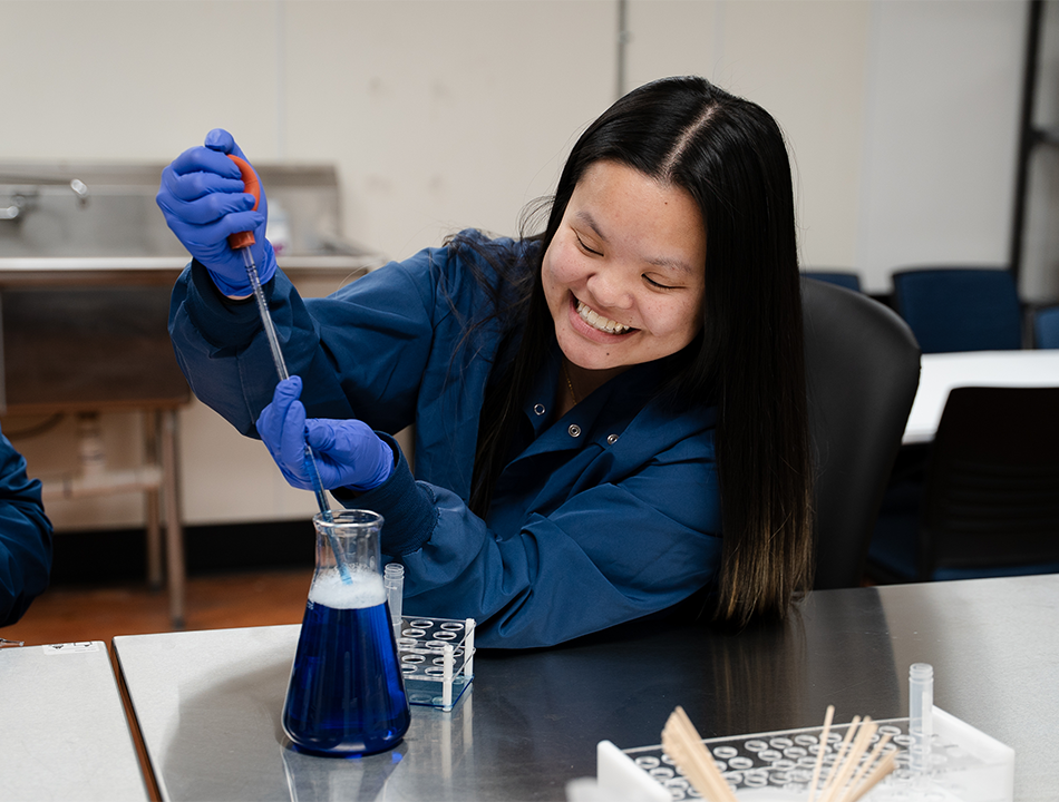 A-woman-in-scrubs-holding-putting-liquid-in-a-beaker A-woman-in-scrubs-holding-putting-liquid-in-a-beaker